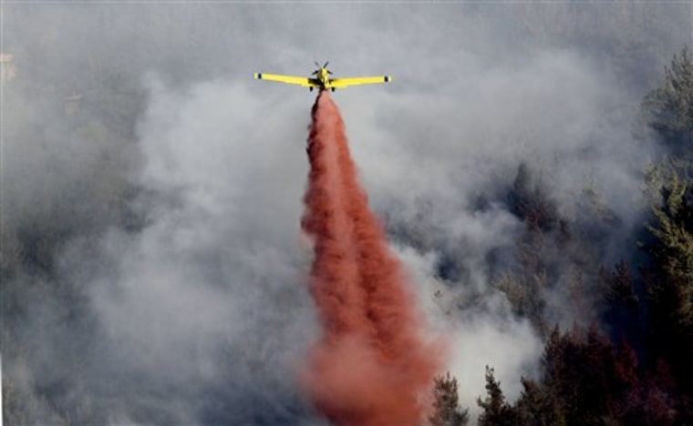 A fire plane drops red fire retardant to try to extinguish fires burning in the forest below Yad Vashem in Jerusalem on Sunday. An out of control wildfire has forced the evacuation of Israel's Holocaust memorial Yad Vashem. 